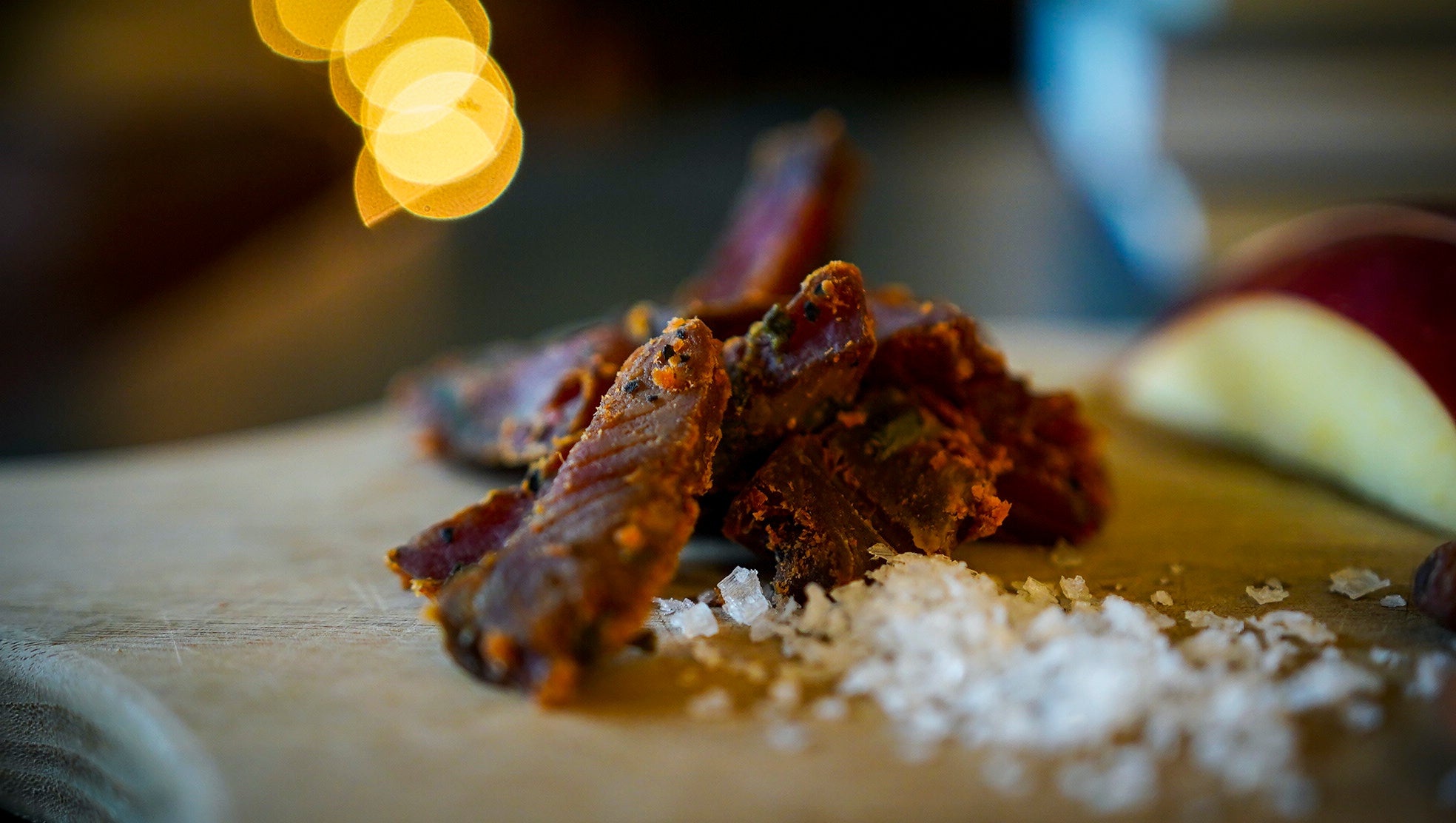 close up of salmon jerky on wood plate